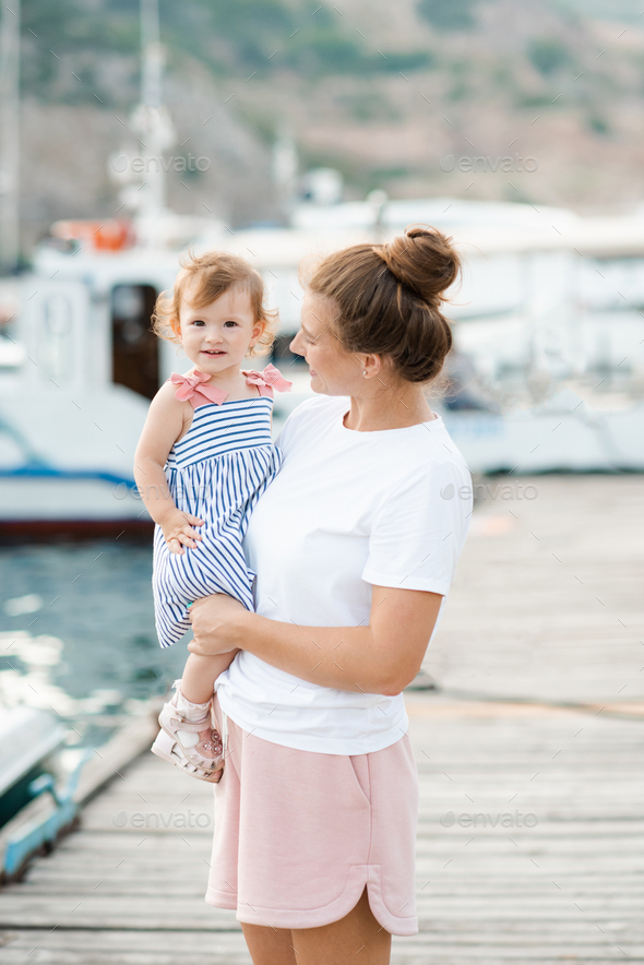 Woman holding her baby girl over sea - Stock Photo - Images