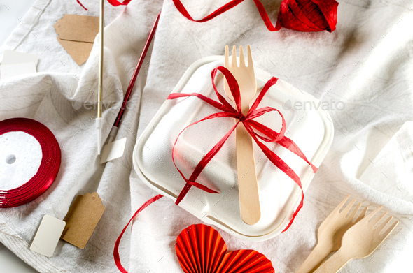 A closed bento cake box with a wooden spoon and tied ribbon