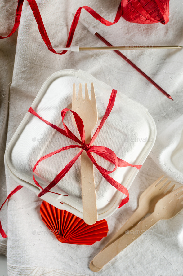 A closed bento cake box with a wooden spoon and tied ribbon