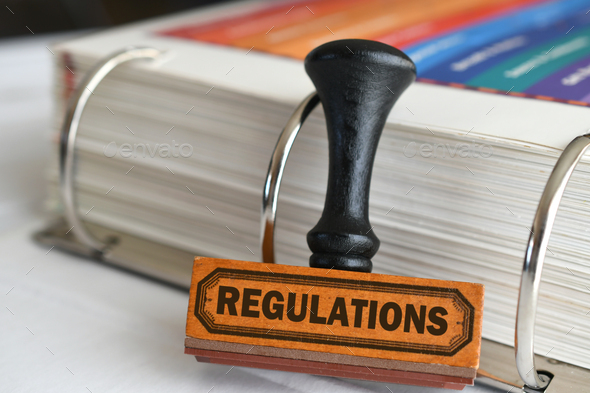 Regulations rubber stamp next to handbook of rules, compliance concept - Stock Photo - Images