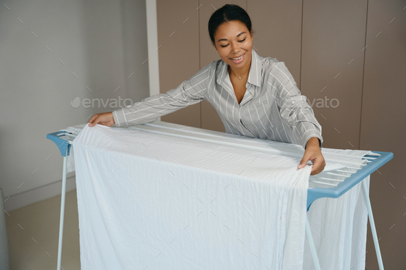 Young maid is hanging a white sheet to dry - Stock Photo - Images