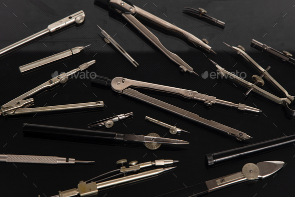 Set of old different compasses. Retro metal compasses and drafting tools on a black background