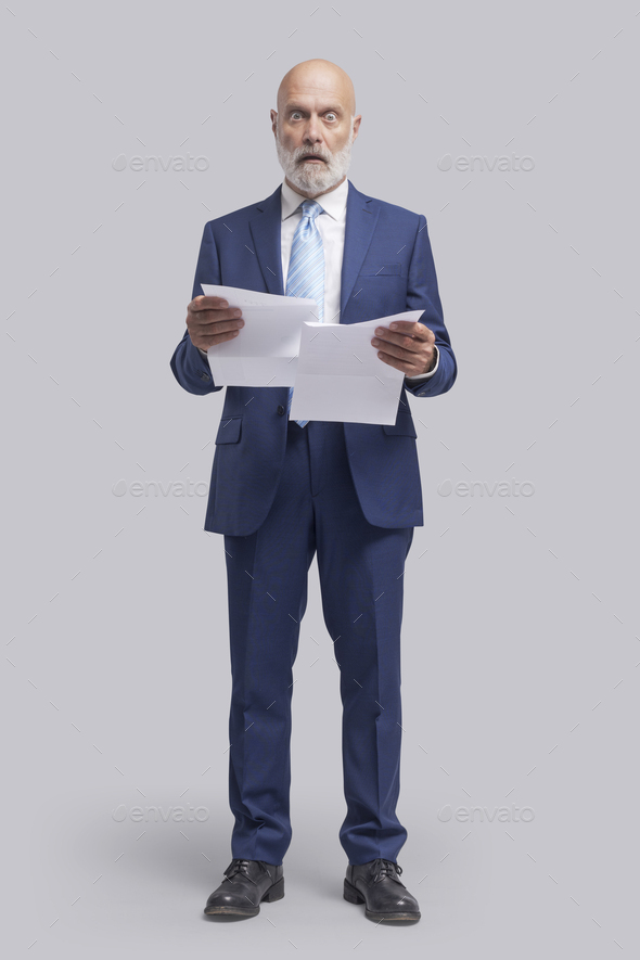 Shocked man holding expensive utility bills and invoices - Stock Photo - Images