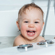 A small smiling beautiful baby bathes in a white bath. Cheerful photography - PhotoDune Item for Sale