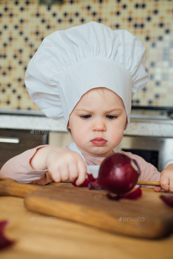 Little girl cooking in the kitchen wearing an apron and a Chef's hat