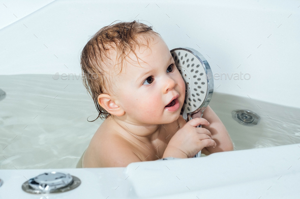 Happy baby child sitting in a bath. Bathing without tears. - Stock Photo - Images