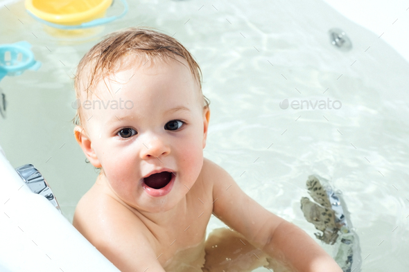 Kid taking bath. Child bathing in bathtub. Little baby playing with water. - Stock Photo - Images