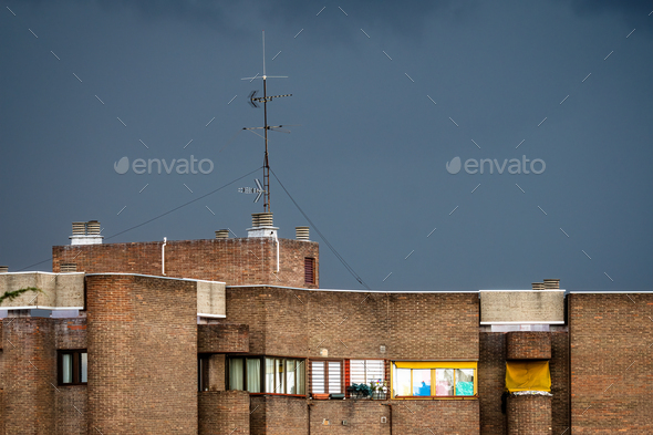 Residential brick building in the city against dark cloudy sky - Stock Photo - Images