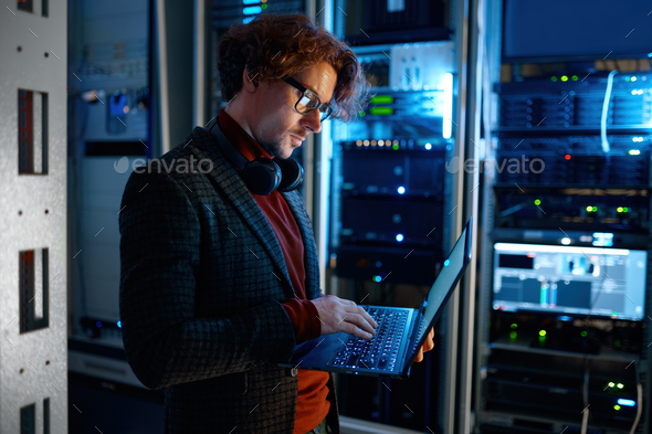 IT technician checking the servers vitals using laptop computer - Stock Photo - Images