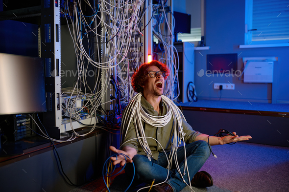 Stressed computer engineer trying to understand network mess - Stock Photo - Images