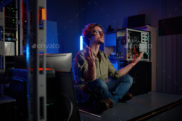 Pensive technician meditating in server room at modern data center - Stock Photo - Images