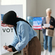 Young Muslim woman in hijab bending over vote booth and making her choice - PhotoDune Item for Sale