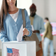 Cropped shot of young woman in casualwear casting ballot paper into box - PhotoDune Item for Sale