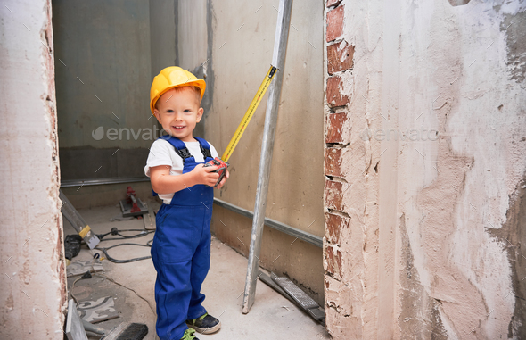 Child with tape measure standing in apartment under renovation.