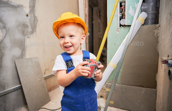 Child with tape measure standing in apartment under renovation.