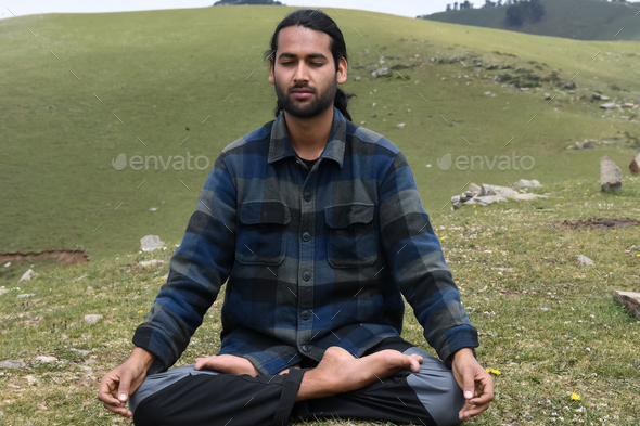 Front view of a young Indian guy practicing Meditation, Yoga in Lotus Pose (Padmasana)