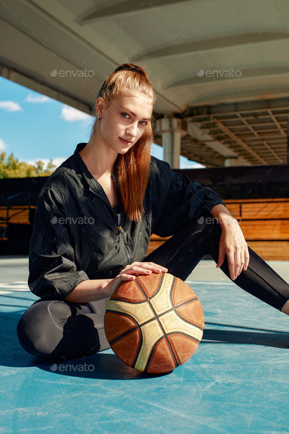 Girl in a black tracksuit on the sports ground with a basketball, women's  basketball, active Stock Photo by Gerain0812