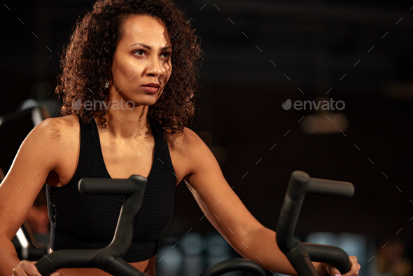 Exercise bike and black woman in the gym for training, cardio training and movement with speed