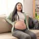 Asian young pregnant woman with big belly has backache, back pain on sofa. - PhotoDune Item for Sale