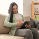 Young asian pregnant woman hands fondle on belly and holding tablet sitting on sofa at home. - PhotoDune Item for Sale
