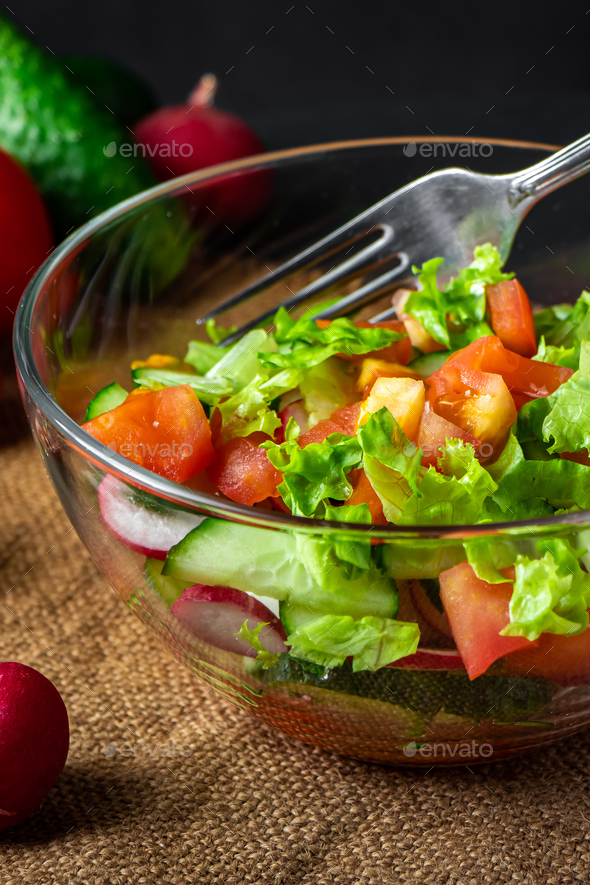 Fresh vegetable salad in a glass bowl on dark background. Vegan organic food, seasonal summer dish. - Stock Photo - Images