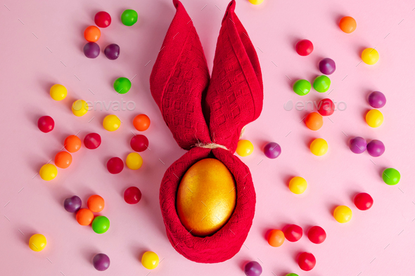 Golden Easter eggs and candies on a pink background. Happy spring holiday - Stock Photo - Images