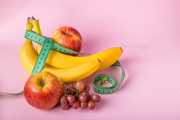 Measuring tape and juicy fruits on a pink background. The concept of diet and weight loss. - Stock Photo - Images