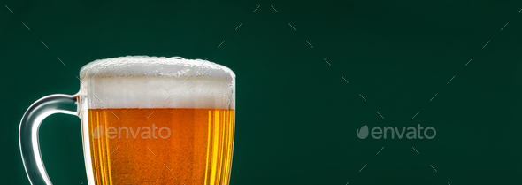 Mug with traditional Irish pale ale on a dark green background. Bubbles in a glass of beer.