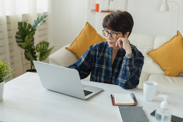 Businesswoman working on laptop computer sitting at home in pajama home wears and managing her - Stock Photo - Images