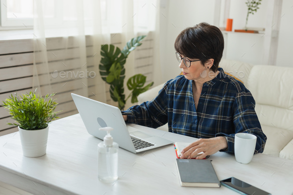 Businesswoman working on laptop computer sitting at home in pajama home wears and managing her - Stock Photo - Images
