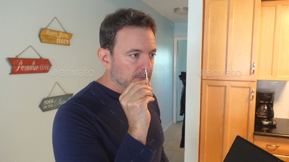 Caucasian man swabs nose with covid19 PCR test at home kit