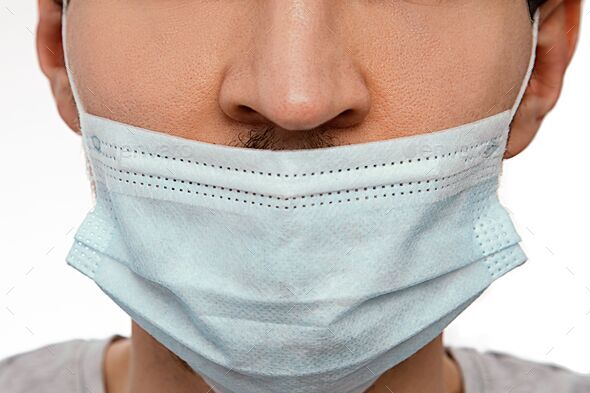 Closeup of a man wearing a face mask under the nose. The wrong way to wear a mask