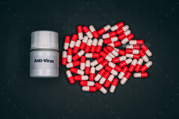 Small pill bottle and a pile of anti-virus red-and-white capsules on the dark background