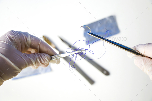Closeup shot of a doctor holding a surgical needle and thread on a white background