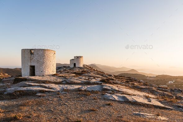 A greek orthodox church with windmills in the background on Amorgos island in Greece.