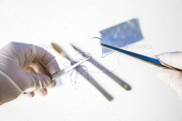 Closeup shot of a doctor holding a surgical needle and thread on a white background