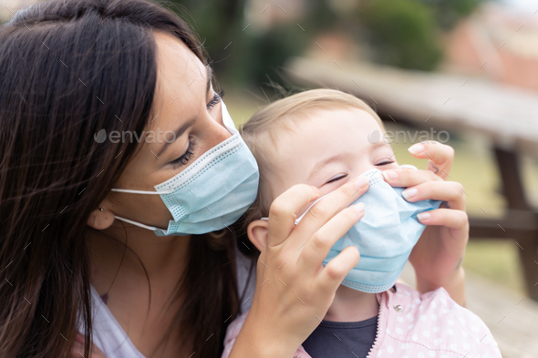 Mother and little girl using protective facial mask outdoors - Stock Photo - Images