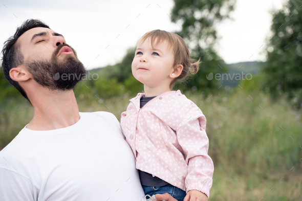 Playful father holding a little girl outdoors - Stock Photo - Images