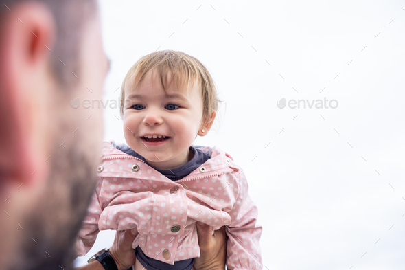 Happy little girl raising in arms of her dad outdoors - Stock Photo - Images