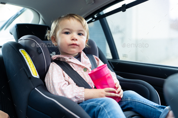Girl looking at camera while drinking water in a car - Stock Photo - Images