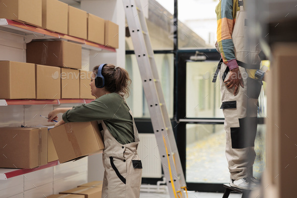 Worker looking at cardboard boxes in storage room - Stock Photo - Images