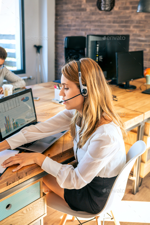 Young woman with headset in customer service of coworking - Stock Photo - Images