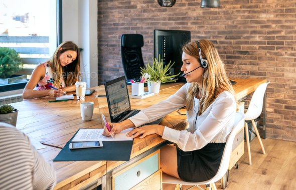 Young woman with headset in customer service of coworking - Stock Photo - Images
