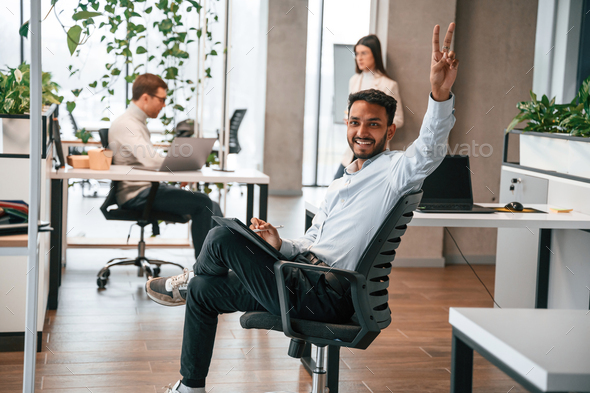 Positive guy is sitting and smiling. Men and woman are working in the office together - Stock Photo - Images
