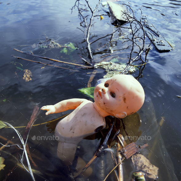 Pollution in public water by a discard,plastic toy doll - Stock Photo - Images