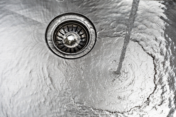 water drains down a stainless steel sink - Stock Photo - Images