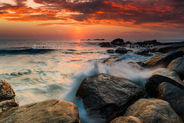Sunset on the rocky shore of tropical sea - Stock Photo - Images