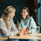 Two woman friends sitting in a cafe watch online media in the phone and laugh. - PhotoDune Item for Sale