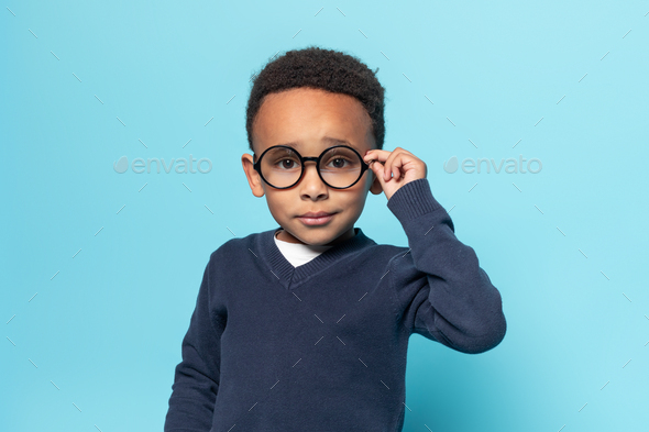 Smart african american little boy in school uniform touching glasses ...