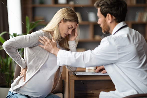 Male Doctor Comforting Pregnant Female Patient Feeling Unwell During Appointment In Clinic